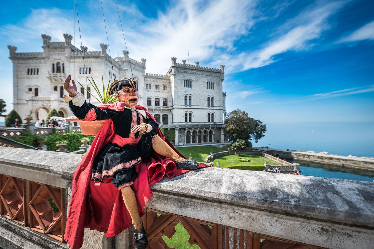 Foto di scena di una marionetta davanti al castello di Miramare di Trieste per lo spettacolo I Piccoli di Podrecca, regia di Paolo Valerio
